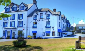 "a large white building with the sign "" commodore 's "" and blue windows is surrounded by a grassy area and a few small boats" at Lion Hotel & Studio Apartments
