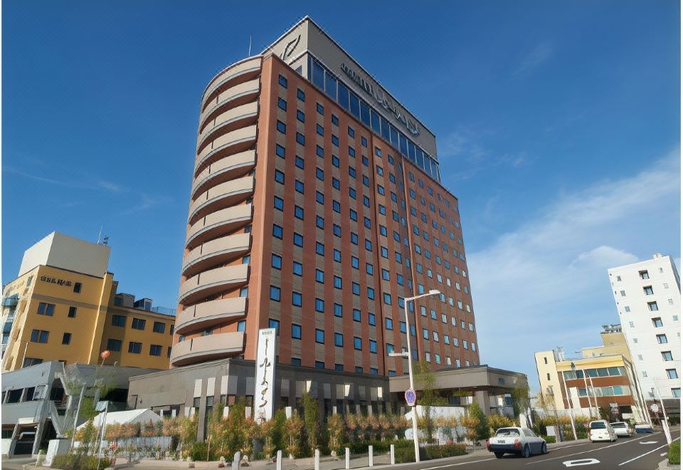 "a tall , modern office building with a circular design and a sign reading "" marriott "" on the front" at Route Inn Grantia Hakodate Ekimae