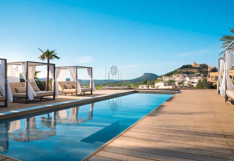 a large swimming pool with a wooden deck and lounge chairs , overlooking a cityscape and hills at Hotel Creu de Tau Art&Spa-Adults Only