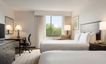 a hotel room with two white beds , a desk , and a window overlooking a garden at DoubleTree by Hilton Hartford - Bradley Airport