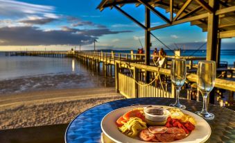 a plate of food is on a table with a glass of wine in front of a pier at Kingfisher Bay Resort