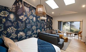a cozy bedroom with a large bed , a couch , and a tv . the room is decorated with blue and white floral wallpaper , creating a at Sea Dragon Kangaroo Island