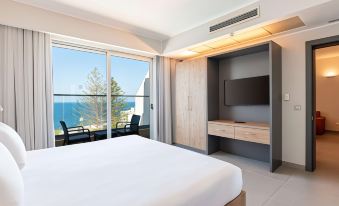 a modern hotel room with a large window offering a view of the ocean , a white bed , and a desk with a television at DoubleTree by Hilton Malta