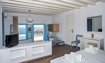 a modern , minimalist living room with white walls and wooden floors , featuring blue doors , white furniture , and a balcony offering views of the ocean at Aeri