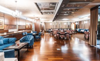 a large , well - lit restaurant with wooden floors and dining tables , some of which have blue chairs at Hotel Holiday