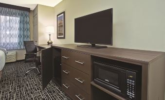 a hotel room with a large flat - screen tv mounted on the wall , along with a desk and a chair at La Quinta Inn & Suites by Wyndham Fairborn Wright-Patterson