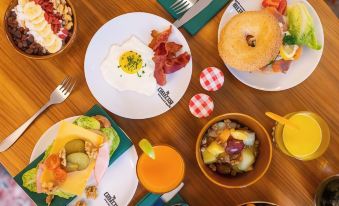 a table is filled with various breakfast foods , including a bagel , eggs , bacon , and orange juice at The Collector