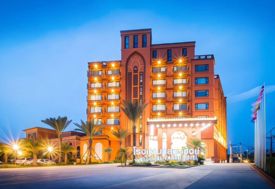 a large , modern hotel building with multiple floors and balconies , surrounded by palm trees and lit up at night at Alfahad Hotel