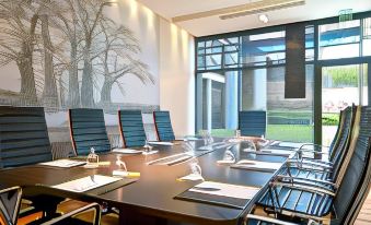 a conference room with a large table surrounded by chairs and a view of trees outside the window at Radisson Blu Hotel, Dakar Sea Plaza