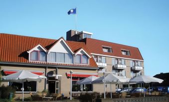 a building with a flag on top and several umbrellas in front of it , all under a clear blue sky at Fletcher Hotel - Restaurant Heiloo