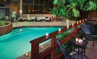 a swimming pool with a wooden fence and chairs , surrounded by greenery and lit up at night at DoubleTree by Hilton Hotel Murfreesboro