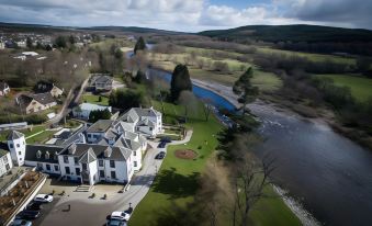 aerial view of a large house surrounded by trees and a body of water , with golf courses visible in the distance at Banchory Lodge Hotel