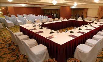 a conference room set up for a meeting with multiple tables and chairs arranged in a semicircle at Mulia Hotel