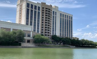 a large building with many windows and balconies is reflected in the water of a lake at Marriott Dallas Las Colinas