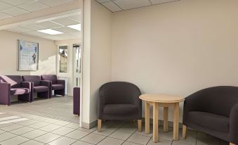 a room with three chairs and a small table in front of a wall with a mirror at Days Inn by Wyndham Sutton Scotney South