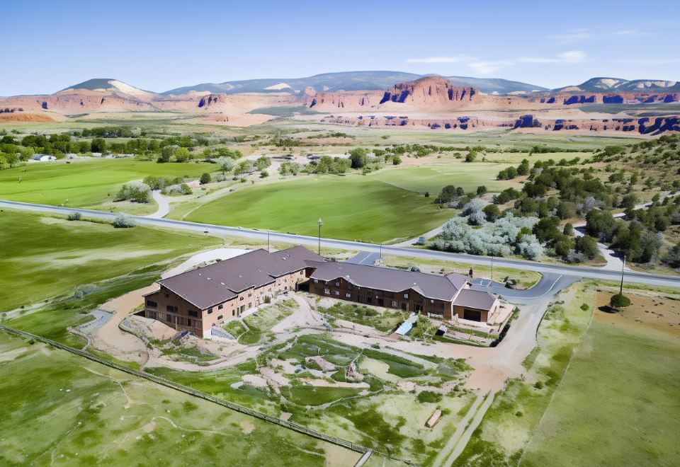 an aerial view of a large building surrounded by green grass and mountains in the background at Red Sands Hotel