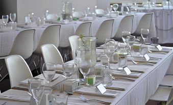 a long table is set with white tablecloths , wine glasses , and various dishes in a formal setting at Lyndoch Hill