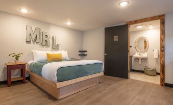"a modern bedroom with a large bed and a bathroom nearby , featuring the word "" mrl "" on the wall" at Mad River Lodge
