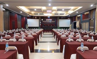 a large conference room with multiple tables covered in red tablecloths and a projector screen on the wall at Novilla Boutique Resort
