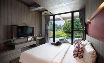 a bedroom with a large bed , white sheets , and a sliding glass door leading to a balcony overlooking trees at Veravian Resort