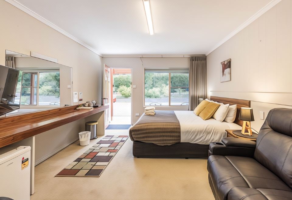 a spacious bedroom with a king - sized bed , a couch , and a tv . the room has a sliding glass door leading to a patio at Black Forest Motel