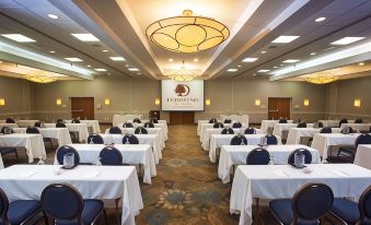 a large conference room with rows of tables and chairs , a stage at the front , and a large chandelier hanging from the ceiling at DoubleTree by Hilton Hotel Murfreesboro