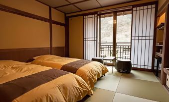 a room with two beds , one on the left and one on the right side of the room at Shima Onsen Kashiwaya Ryokan