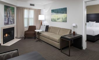 a modern living room with a beige couch , wooden coffee table , and large window curtains at Residence Inn Boston Westford