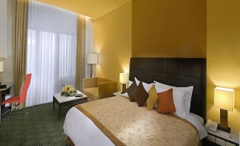 a large bed with a brown headboard and white sheets is in a room with yellow walls at Golden Flower by Kagum Hotels