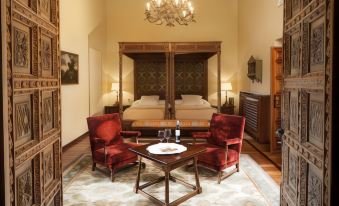 a bedroom with a wooden canopy bed , red chairs , and a dining table in the room at Parador de Leon - San Marcos