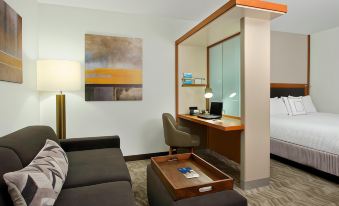 a hotel room with a comfortable bed , a desk with a laptop , and a chair at SpringHill Suites Madera