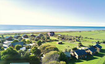 a picturesque rural landscape with houses and green fields , situated near the ocean under a clear blue sky at Shining Star Beachfront Accommodation