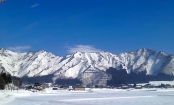 a snow - covered mountain range with a blue sky and clear skies , and a small town in the foreground at Ryugon