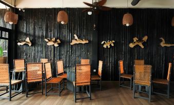 a restaurant with wooden tables and chairs , a ceiling fan , and black walls decorated with wooden sculptures at The Happy 8 Retreat @ Kuala Sepetang