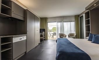 a hotel room with a king - sized bed , a tv , and a balcony overlooking the ocean at Suite Home Porticcio