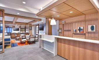 a modern hotel lobby with a wooden reception desk and a tv mounted on the wall at Hyatt House Provo/Pleasant Grove