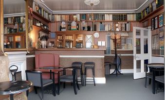 a cozy coffee shop with a variety of chairs , tables , and bookshelves filled with books at Canterbury Hotel