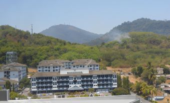 a large building with a gray roof is surrounded by trees and mountains , with smoke rising from the chimneys at HIG Hotel
