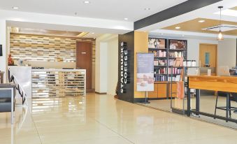 a modern , minimalist store with wooden floors and white walls , featuring various products on shelves and tables at M Hotel