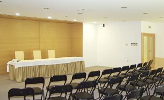 a large , empty conference room with rows of black chairs arranged in front of a white table at Stay Hotel Guimarães Centro