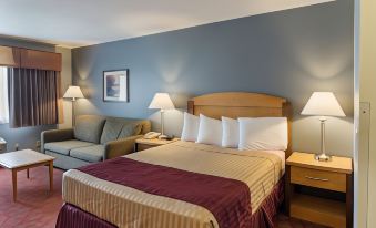 a large bed with a wooden headboard and multiple pillows is in a hotel room at Boarders Inn & Suites by Cobblestone Hotels - Superior/Duluth