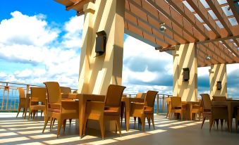 an outdoor dining area with wooden tables and chairs under a pergola , overlooking the ocean at Timberland Highlands Resort