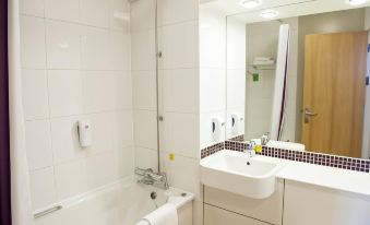 a bathroom with a white bathtub , sink , and mirror , as well as towels and toiletries on the counter at Swindon North