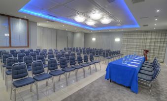 a conference room with rows of chairs and a large blue table in the center at Alexandra Hotel