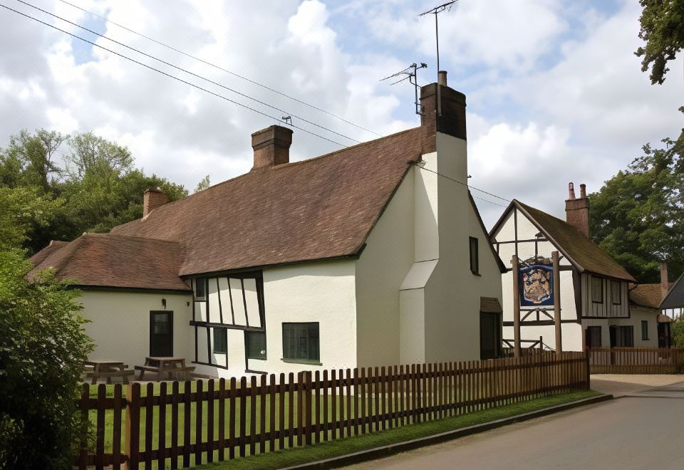 a white house with a thatched roof and a wooden fence in front of it at The Brocket Arms