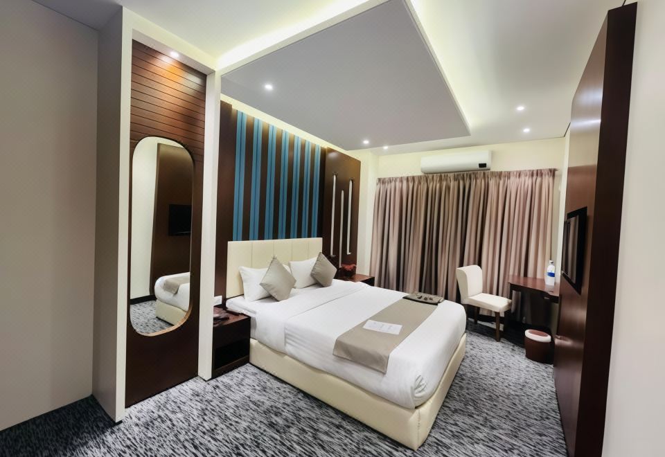 a modern hotel room with a large bed , two nightstands , and a tv on the wall at Richmond Hotel Sylhet
