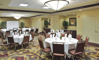 a large dining room with multiple round tables covered in white tablecloths , set for a formal event at Hilton Garden Inn Clovis