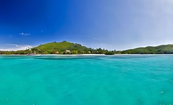 a beautiful view of a tropical island with clear blue water and green hills in the background at Navutu Stars Resort