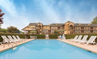 an outdoor swimming pool surrounded by a hotel , with several lounge chairs placed around the pool area at St. James Hotel Selma, Tapestry Collection by Hilton