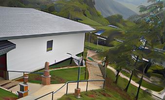 a white building is nestled in a mountainous area with a walkway leading up to it at AYANA Holiday Resort